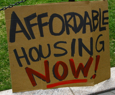 "Affordable housing now" written on cardboard sign.