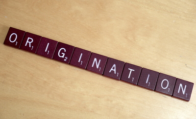 Origination spelled out with Scrabble game pieces